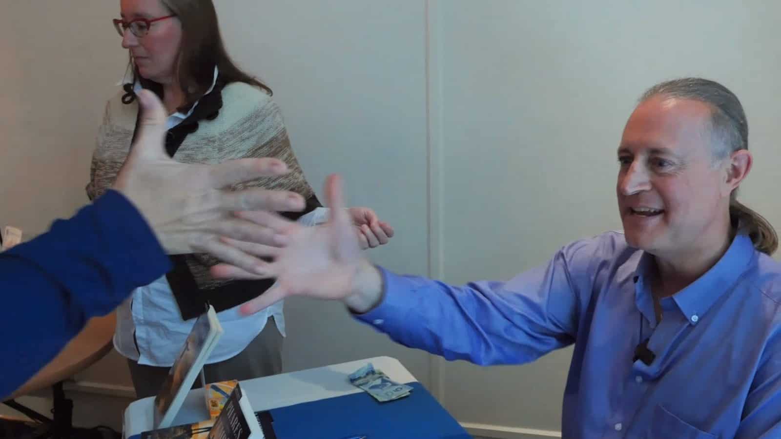 Pascal N. Paquette reaching out his hand to a reader at his book-signing table