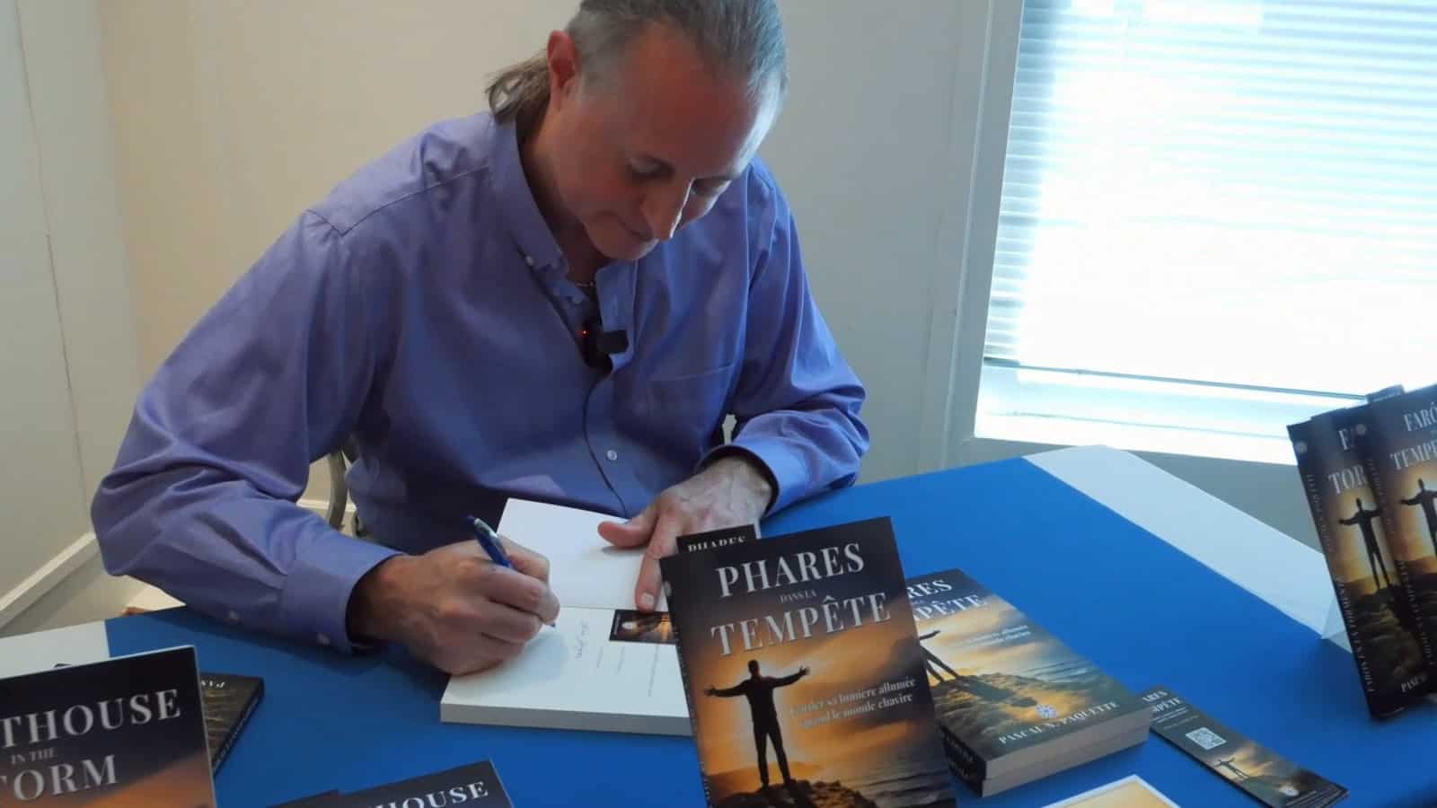 Pascal N. Paquette signing a copy of Phares dans la Tempête