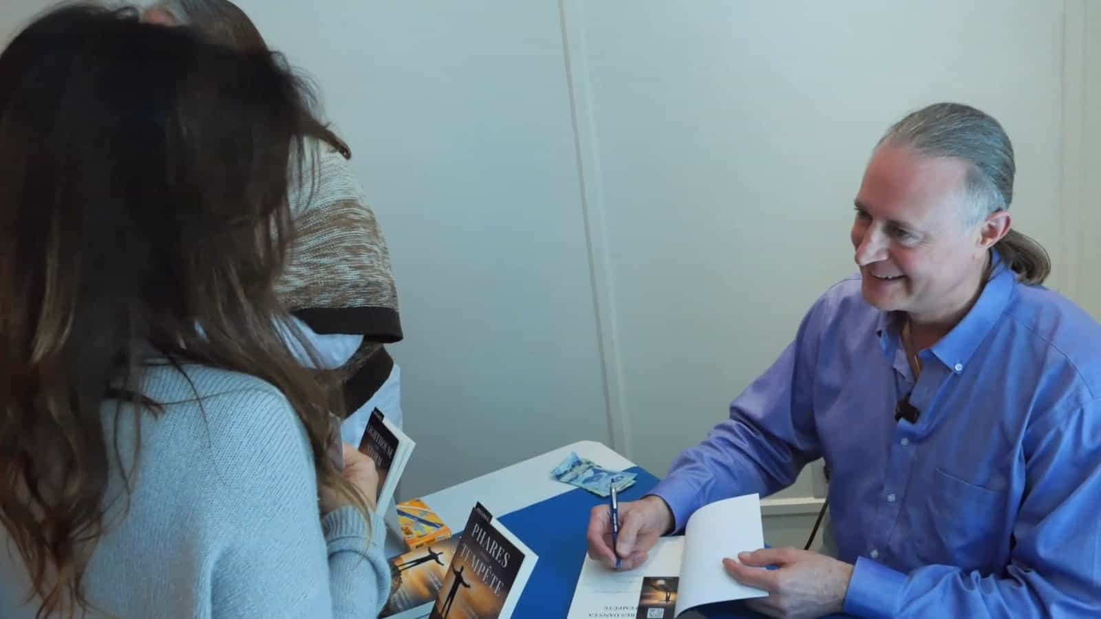 Pascal N. Paquette signe un livre en riant avec une lectrice