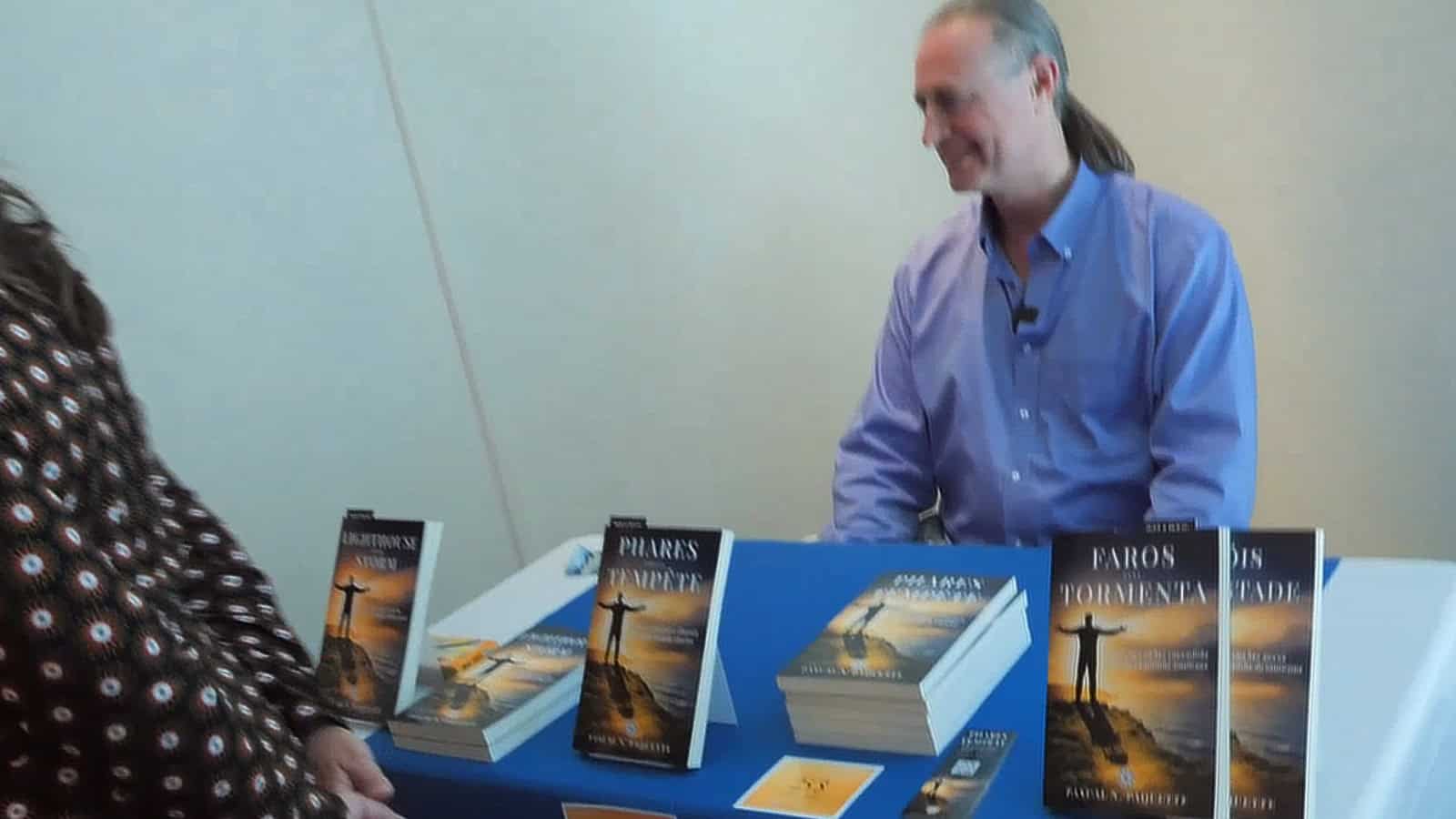 Pascal N. Paquette seated behind the table of his books